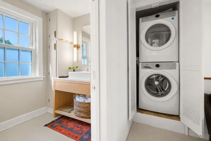 full bathroom with tiled shower tub, and stackable washer/dryer, located on the second level.
