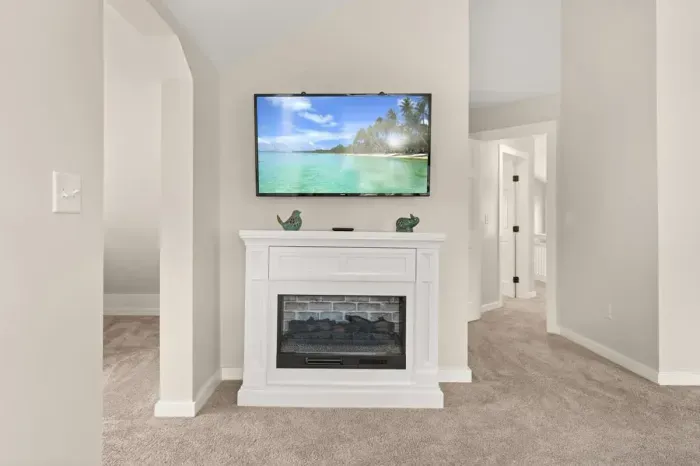 A cozy electric fireplace and sleek TV mounted on the wall, both perfectly placed to enjoy from the comfort of the master bedroom.