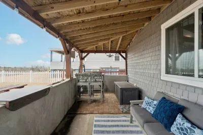 Covered front porch on the sand with dining table and small outdoor sofa