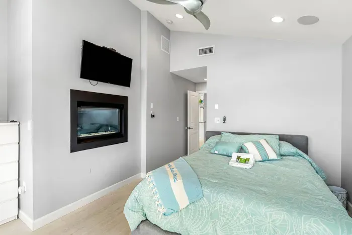 Primary bedroom in the penthouse with a gas fireplace, Queen bed, Smart TV, and access to the rooftop deck. Oceans views and clean linens provided!