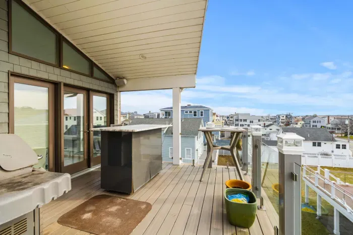 The back deck of the penthouse with Salisbury marsh views, and access via the back staircase to the backyard and parking area. Please note this grill is for owner use only. 