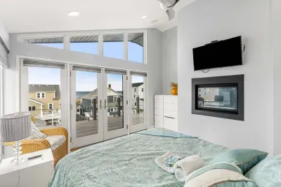 Primary bedroom in the penthouse with a gas fireplace, Queen bed, Smart TV, and access to the rooftop deck. Oceans views and clean linens provided!