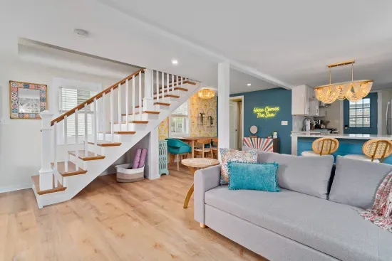 Open, living room, kitchen & dining room with "here comes the sun" neon light sign, flat screen smart TV & sleeper sofa. Private front covered deck with seating, back private deck with picnic table, yoga mats, dining table for 6 pp &  island for 2pp