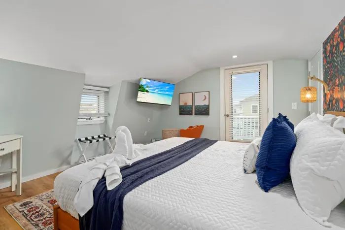 Primary bedroom with king bed, flat smart TV, work-from-home desk and balcony facing the ocean.