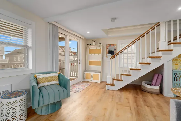 Open, living room, kitchen & dining room with "here comes the sun" neon light sign, flat screen smart TV & sleeper sofa. Private front covered deck with seating, back private deck with picnic table, yoga mats, dining table for 6 pp &  island for 2pp