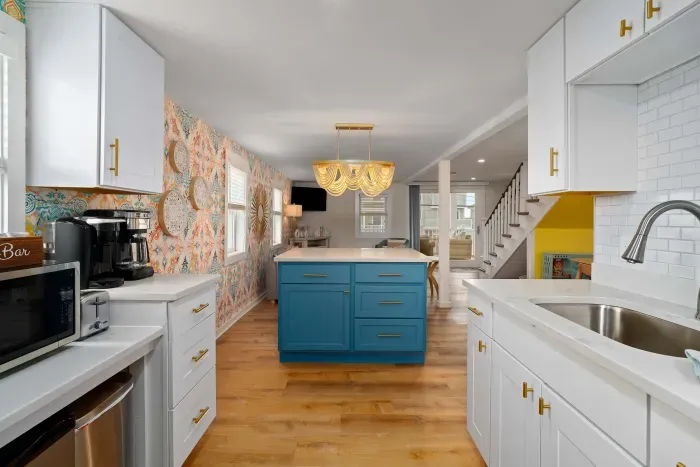 Open, living room, kitchen & dining room with "here comes the sun" neon light sign, flat screen smart TV & sleeper sofa. Private front covered deck with seating, back private deck with picnic table, yoga mats, dining table for 6 pp &  island for 2pp