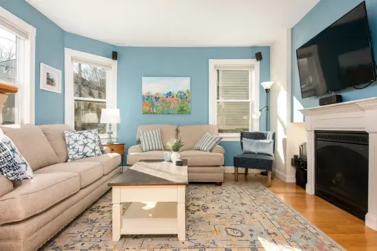 Large, sunny and comfortable living room with mounted TV and electric fireplace for all guests to enjoy.
