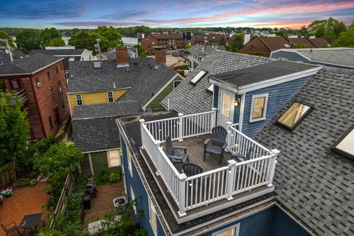 Private rooftop deck with seating, string lights, and partial views of the Merrimack River