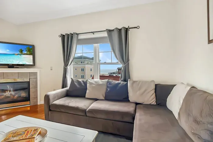Living room with ocean views featuring both a sectional and pull-out couch, and access to the private balcony!