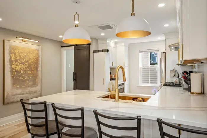 High end kitchen featuring sleek quartz countertops. Seating for four at the bar.