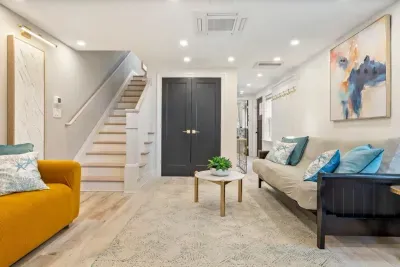 Enter into the living area where there is a large smart TV, a couch, and a futon. The laundry closet is located in this room.
