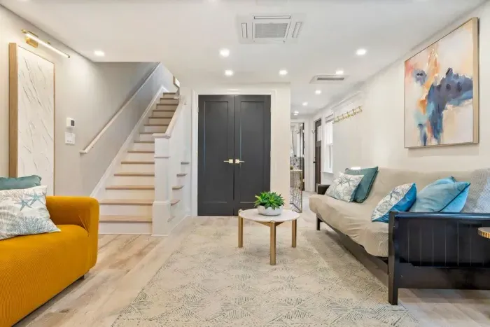 Enter into the living area where there is a large smart TV, a couch, and a futon. The laundry closet is located in this room.