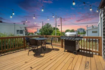 Deck with 4-person outdoor dining table, gas grill, and string lights