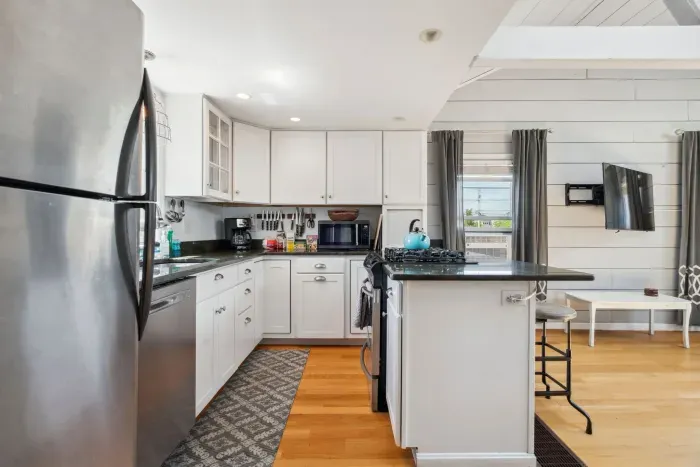 Fully equipped kitchen with all necessary appliances, 3-seater eat-in counter, and 6-person dining table