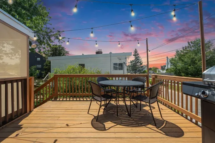 Deck with 4-person outdoor dining table, gas grill, and string lights
