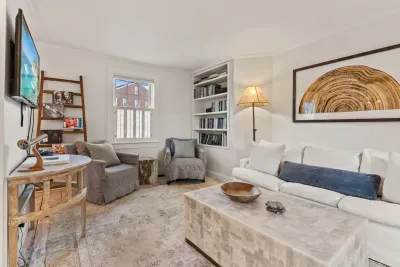 Living room with smart TV, couch, accent chairs and entrance to private deck/garden.