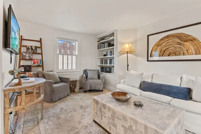 Living room with smart TV, couch, accent chairs and entrance to private deck/garden.