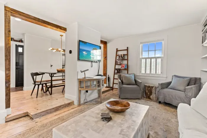Living room with smart TV, couch, accent chairs and entrance to private deck/garden.