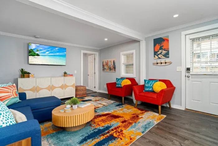 First Living Room (one of 2 living rooms at the property), with "go with the flow" neon light sign, flat screen smart TV and sleeper sofa
