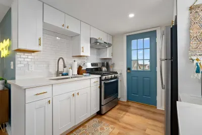 Living room/kitchen #2, on the 2nd level, with "here comes the sun" neon light sign, flat screen smart TV & sleeper sofa. Private front covered deck with seating, back private deck with picnic table, yoga mats, dining table for 6 pp & island for 2pp