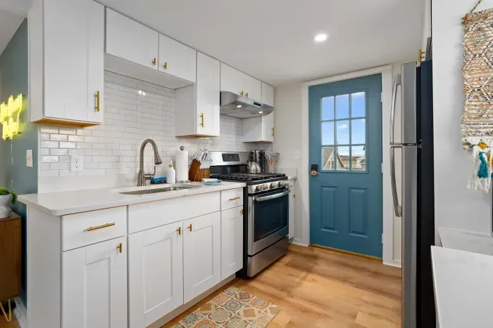 Living room/kitchen #2, on the 2nd level, with "here comes the sun" neon light sign, flat screen smart TV & sleeper sofa. Private front covered deck with seating, back private deck with picnic table, yoga mats, dining table for 6 pp & island for 2pp