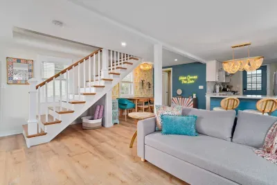 Living room/kitchen #2, on the 2nd level, with "here comes the sun" neon light sign, flat screen smart TV & sleeper sofa. Private front covered deck with seating, back private deck with picnic table, yoga mats, dining table for 6 pp & island for 2pp