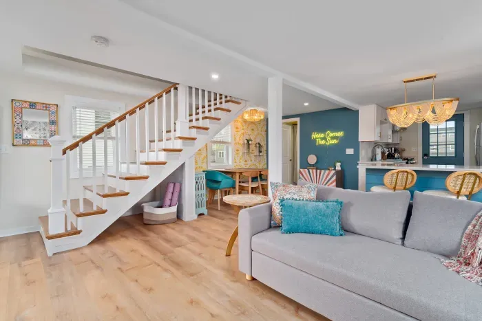 Living room/kitchen #2, on the 2nd level, with "here comes the sun" neon light sign, flat screen smart TV & sleeper sofa. Private front covered deck with seating, back private deck with picnic table, yoga mats, dining table for 6 pp & island for 2pp