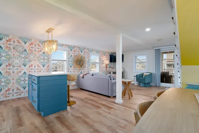 Living room/kitchen #2, on the 2nd level, with "here comes the sun" neon light sign, flat screen smart TV & sleeper sofa. Private front covered deck with seating, back private deck with picnic table, yoga mats, dining table for 6 pp & island for 2pp