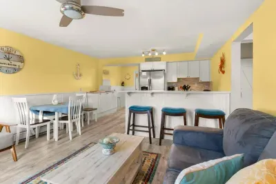 Newly renovated, open kitchen & living room with all new appliances, breakfast bar, 4-seat dining table, couch, accent chair and flat screen smart Roku TV.