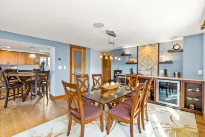 Dining area in the Namaste unit with seating for 6. Wet bar is located behind it with a sink and 2 drink fridges. There is extra drink wear in the glass door cabinet.