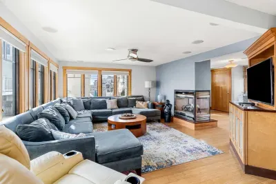 🛋️ Namaste Unit Living Room – Bright and spacious with hardwood floors, cozy seating, smart TV, and a modern double-sided fireplace. The spiral staircase heads up to the yoga unit!