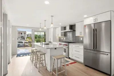 Fully equipped open kitchen and living room with large island, high-end appliances, kitchen table, washer/dryer, smart tv