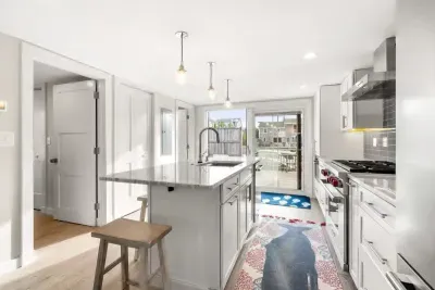 Fully equipped open kitchen and living room with large island, high-end appliances, kitchen table, washer/dryer, smart tv