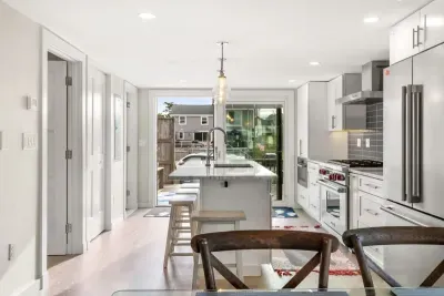 Fully equipped open kitchen and living room with large island, high-end appliances, kitchen table, washer/dryer, smart tv