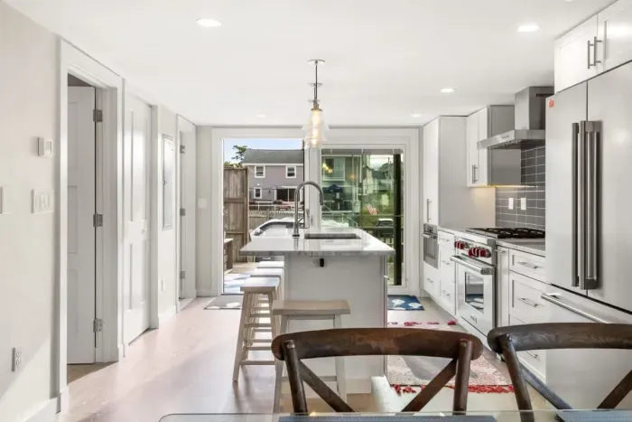 Fully equipped open kitchen and living room with large island, high-end appliances, kitchen table, washer/dryer, smart tv