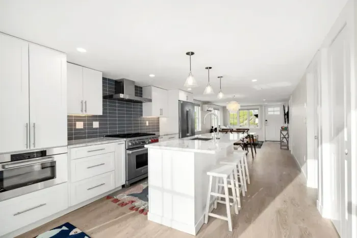 Fully equipped open kitchen and living room with large island, high-end appliances, kitchen table, washer/dryer, smart tv