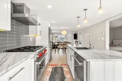 Fully equipped open kitchen and living room with large island, high-end appliances, kitchen table, washer/dryer, smart tv