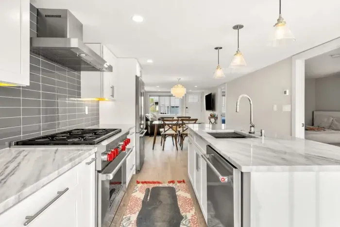 Fully equipped open kitchen and living room with large island, high-end appliances, kitchen table, washer/dryer, smart tv