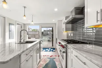 Fully equipped open kitchen and living room with large island, high-end appliances, kitchen table, washer/dryer, smart tv