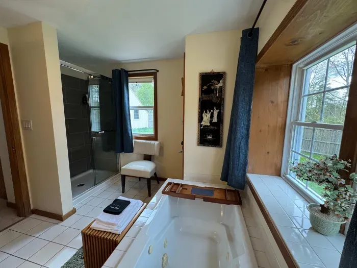 The primary bedroom ensuite with a new standing shower, jetted soaking tub, and clean towels are provided.