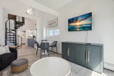 Cozy dining area and living room with 4-person dining table, sleeper sofa, smart TV, and access to private balcony