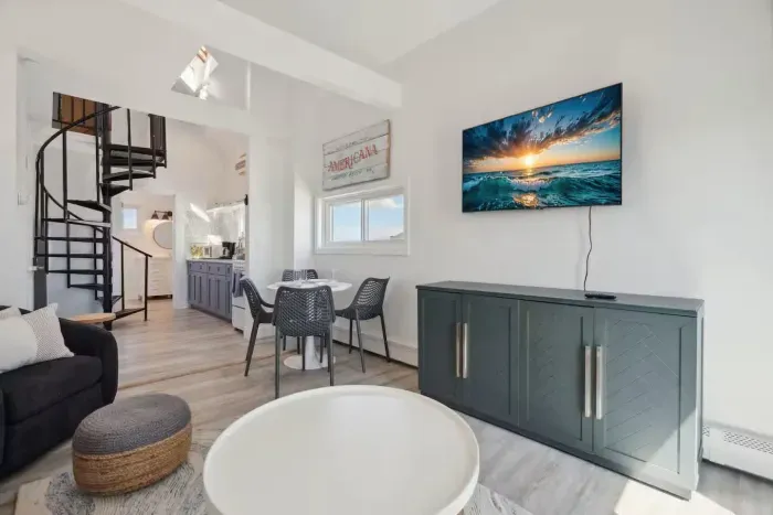 Cozy dining area and living room with 4-person dining table, sleeper sofa, smart TV, and access to private balcony