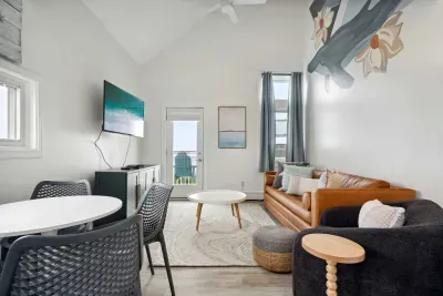 Cozy dining area and living room with 4-person dining table, sleeper sofa, smart TV, and access to private balcony