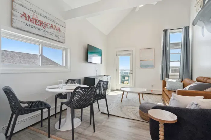 Cozy dining area and living room with 4-person dining table, sleeper sofa, smart TV, and access to private balcony