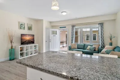 Open living room & kitchen with sleeper sofa, mounted smart TV, strong WiFi and fully-equipped kitchen