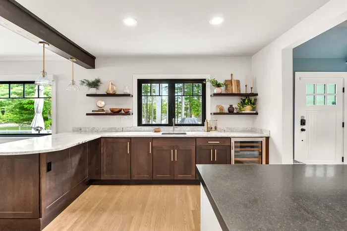 This stylish wet bar connects the kitchen to the outdoors through a fold-open accordion window, with outdoor bar seating right on the other side — plus a wine fridge and ice maker