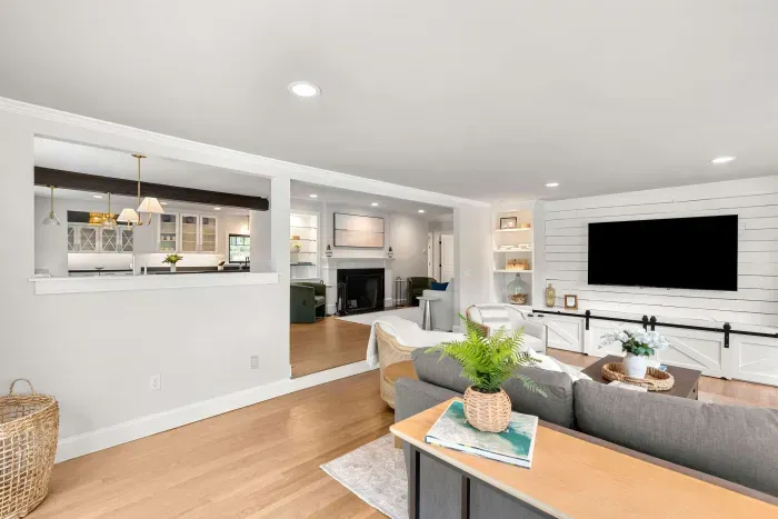 The heart of the home. A sprawling sectional, smart TV, and two lounge chairs — plus sliders that blur the line between inside and out, opening to a stunning creekside deck