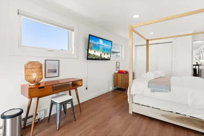 Bedroom with queen bed, sleeper sofa, work desk, smart TV and slider to private back deck