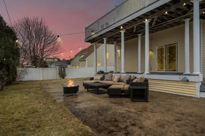 Spacious fenced in backyard with firepit and outdoor couch setup