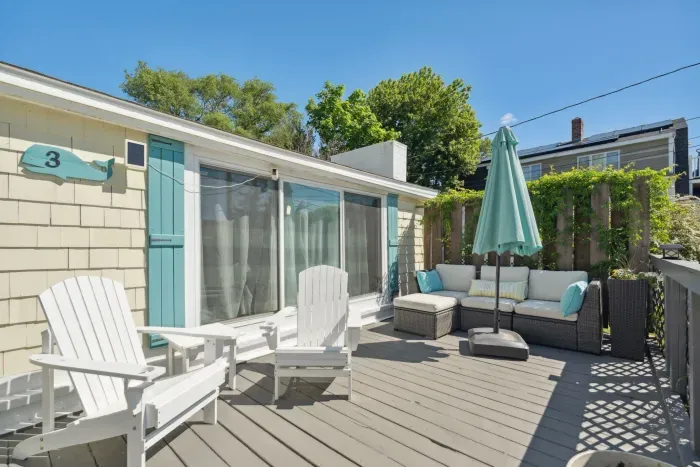 Front deck with outdoor couch, umbrella, and Adirondack chairs